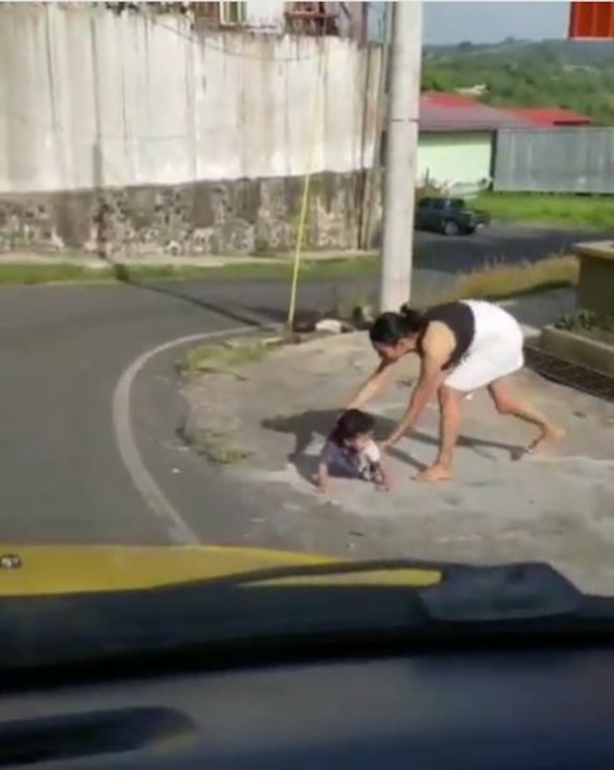 Bebé que estaba gateando hacia la calle es rescatado por su madre, mientras un hombre lo graba todo. Video